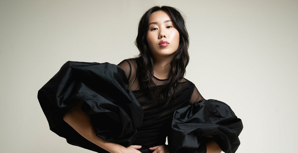 Woman wearing a black dress with puffed sleeves against a plain background