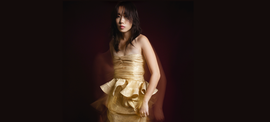 Woman wearing a gold dress against a dark background